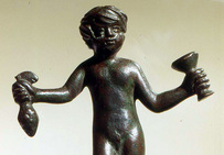 Statuette en bronze représentant Bacchus enfant tenant une grappe de raisin et un vase.   Musée de l'Arles antique.